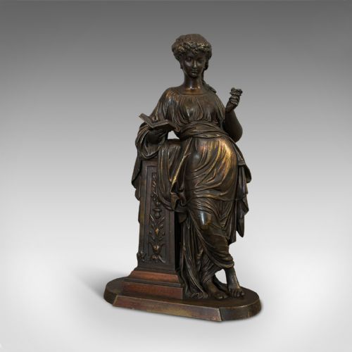 fig 2. An antique dark bronze figure depicting a draped female maiden holding a book and leaning against a carved pedestal.