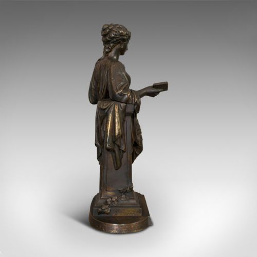 fig 3. An antique dark bronze figure depicting a draped female maiden holding a book and leaning against a carved pedestal.