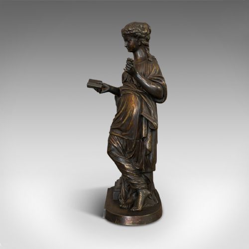 fig 4. An antique dark bronze figure depicting a draped female maiden holding a book and leaning against a carved pedestal.