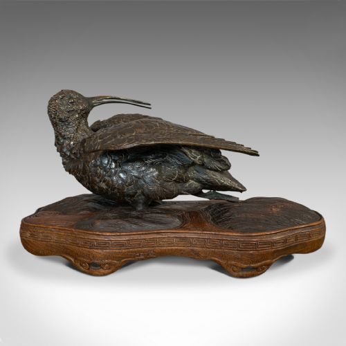 fig 3. An antique bronze sculpture depicting a curlew bird with outstretched wings, set upon a carved mahogany base.