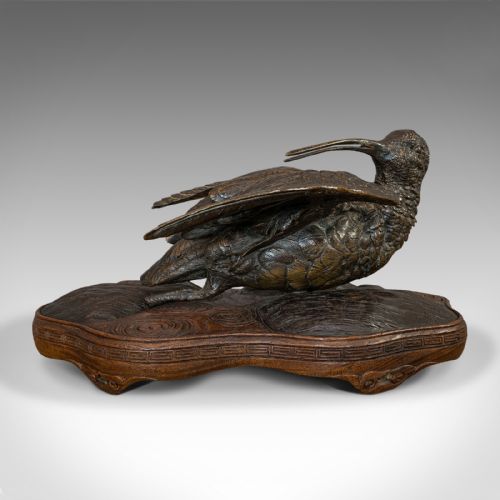 fig 4. An antique bronze sculpture depicting a curlew bird with outstretched wings, set upon a carved mahogany base.