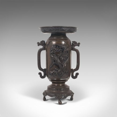fig 1. A dark brown bronze Japanese Meiji period vase featuring relief carving of a bird on a branch, ornate handles, and a pedestal base.