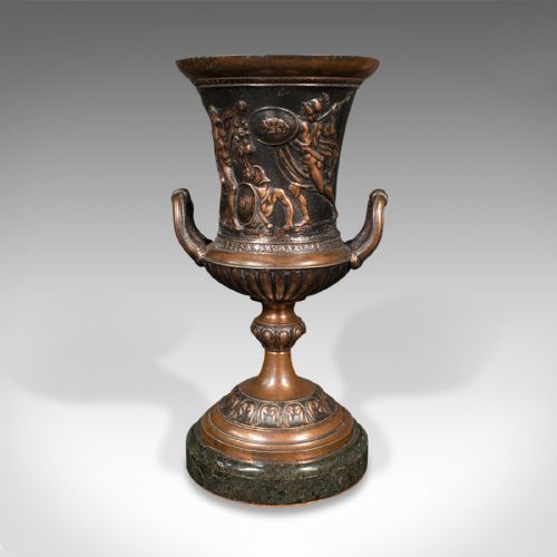 fig 2. A pair of patinated bronze urns featuring low-relief classical figures set upon dark circular marble bases.