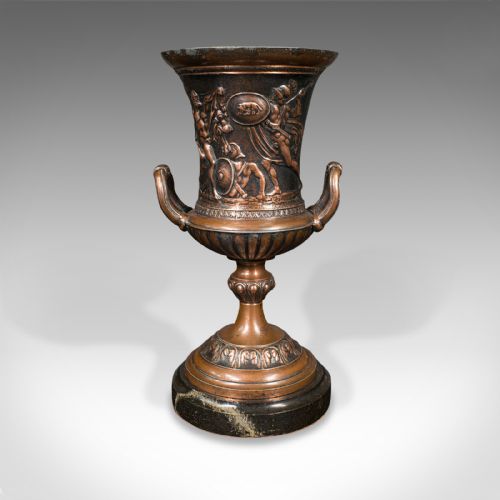 fig 3. A pair of patinated bronze urns featuring low-relief classical figures set upon dark circular marble bases.