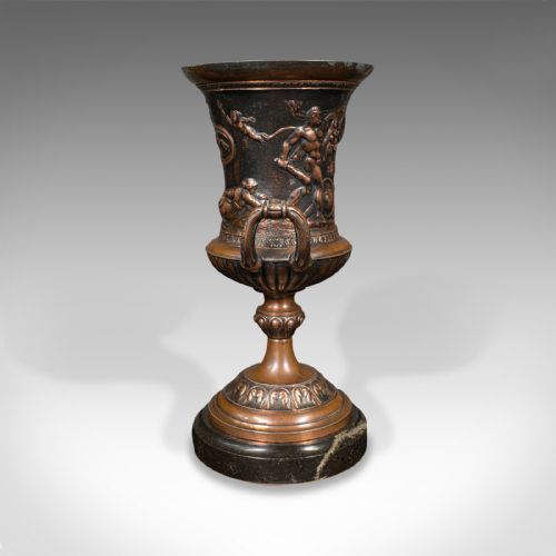 fig 4. A pair of patinated bronze urns featuring low-relief classical figures set upon dark circular marble bases.