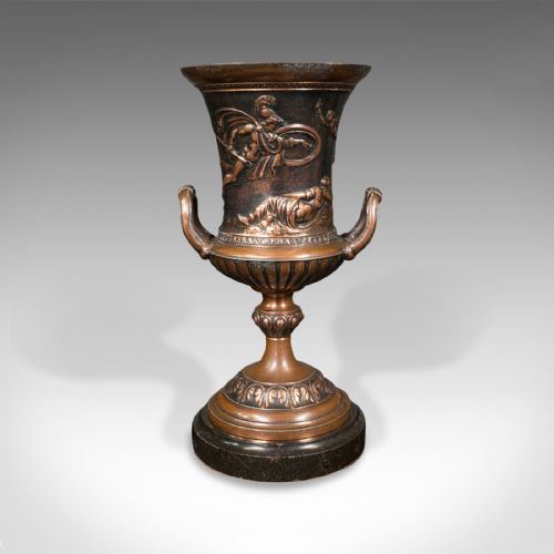 fig 5. A pair of patinated bronze urns featuring low-relief classical figures set upon dark circular marble bases.