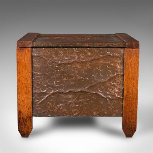 fig 1. An Edwardian oak coal keeper featuring an open hinged lid and textured hammered copper panels mounted within a solid wooden frame.
