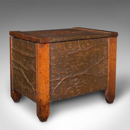 fig 2. An Edwardian oak coal keeper featuring an open hinged lid and textured hammered copper panels mounted within a solid wooden frame.
