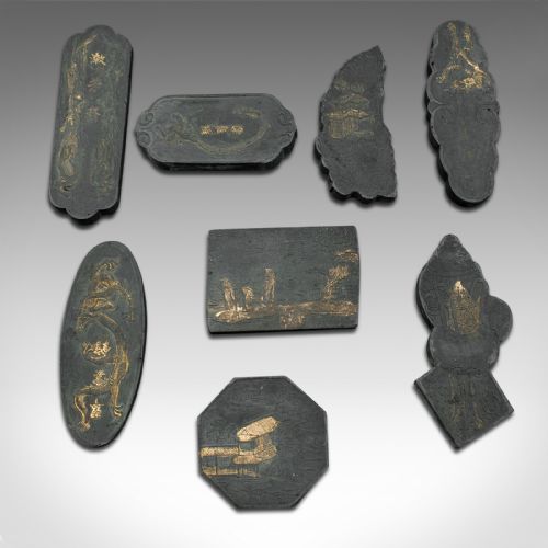 fig 1. An eight-piece set of black Japanese calligraphic ink blocks in various geometric and organic shapes with gold detailed relief, alongside a patterned storage box.