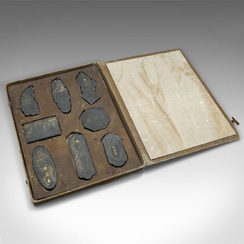 fig 2. An eight-piece set of black Japanese calligraphic ink blocks in various geometric and organic shapes with gold detailed relief, alongside a patterned storage box.