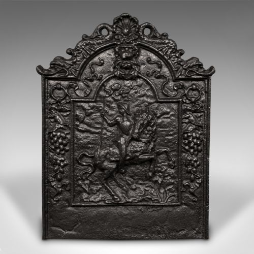 fig 1. A dark cast iron Georgian fireback decorated with an equestrian relief figure surrounded by detailed foliate and scroll cresting.