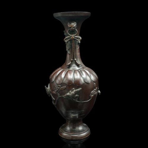 fig 2. A dark brown patinated bronze stem vase featuring high-relief carvings of birds among foliage, stylised mask handles with drop rings, and a fluted rim.