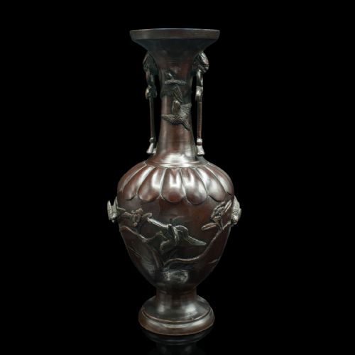 fig 3. A dark brown patinated bronze stem vase featuring high-relief carvings of birds among foliage, stylised mask handles with drop rings, and a fluted rim.