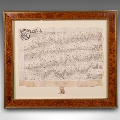 fig 1. A seventeenth-century handwritten vellum indenture with a wax seal, presented inside a light mount and a wide burr wood style frame.