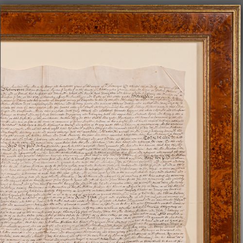 fig 4. A seventeenth-century handwritten vellum indenture with a wax seal, presented inside a light mount and a wide burr wood style frame.