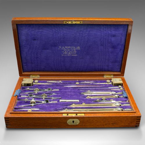 fig 2. An open mahogany wood box with a purple velvet lining containing an array of antique brass drafting compasses and ruling pens.
