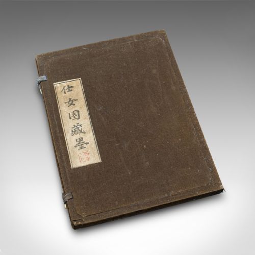 fig 1. An open brown fabric-lined case containing eight black ink blocks of varied geometric shapes decorated with gilded figurative engravings.