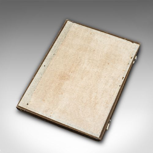 fig 2. An open brown fabric-lined case containing eight black ink blocks of varied geometric shapes decorated with gilded figurative engravings.