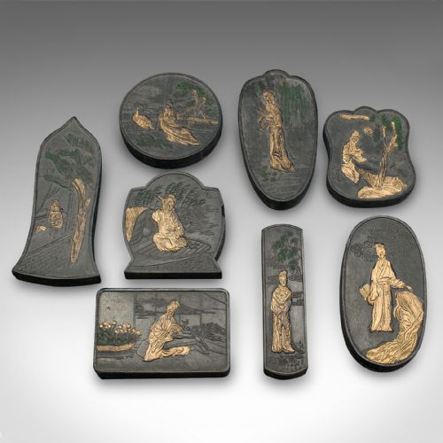 fig 3. An open brown fabric-lined case containing eight black ink blocks of varied geometric shapes decorated with gilded figurative engravings.