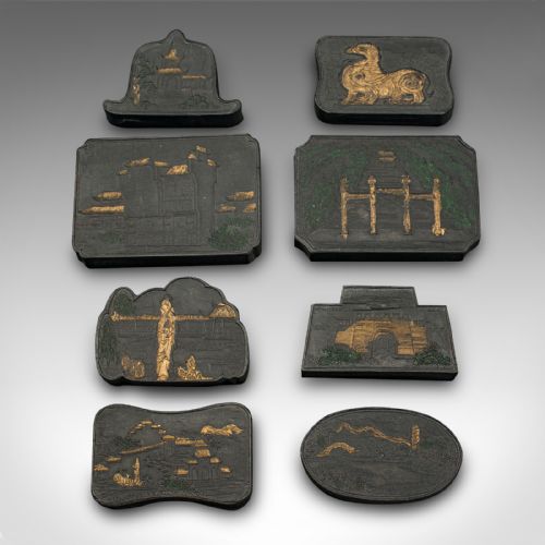 fig 3. An open fabric-lined box displaying a set of eight black Chinese ink blocks adorned with gold and green moulded architectural and figural motifs.