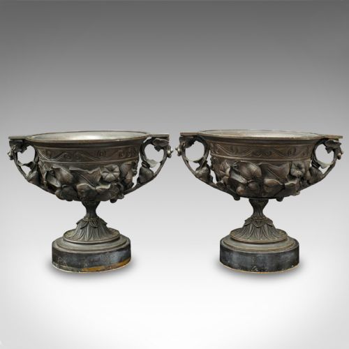 fig 1. A pair of antique cast bronze goblets with high floral relief moulding resting on circular dark bases.