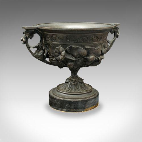 fig 2. A pair of antique cast bronze goblets with high floral relief moulding resting on circular dark bases.