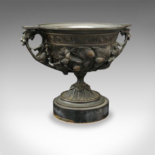 fig 3. A pair of antique cast bronze goblets with high floral relief moulding resting on circular dark bases.