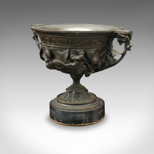 fig 4. A pair of antique cast bronze goblets with high floral relief moulding resting on circular dark bases.
