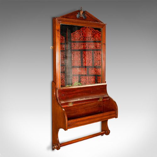 fig 1. A Victorian mahogany wall-mounted valet mirror featuring a pediment top, rectangular glass plate, cylinder glove box, and lower hanging rail.