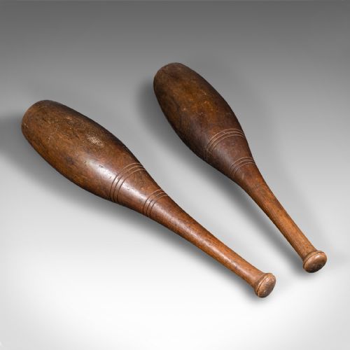 fig 1. A pair of turned brown beech wood Indian exercise clubs featuring incised decorative ring grooves on the handles.