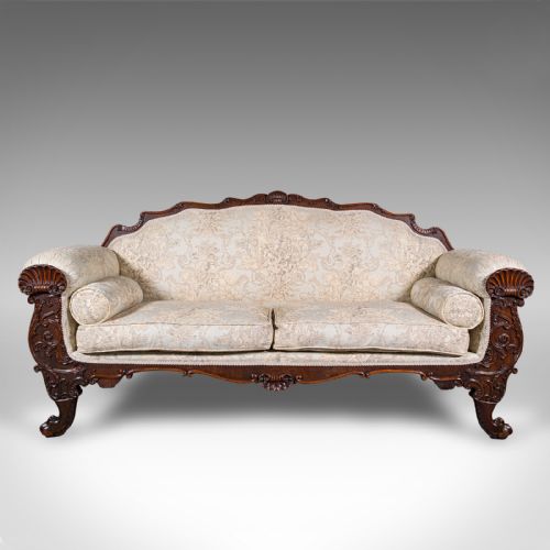 fig 1. A William IV carved mahogany settee featuring cream patterned damask upholstery, scroll arms, bolster cushions, and detailed paw feet.