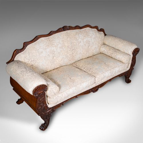 fig 5. A William IV carved mahogany settee featuring cream patterned damask upholstery, scroll arms, bolster cushions, and detailed paw feet.
