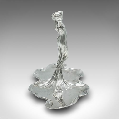 fig 2. A silver-toned Art Nouveau metal card tray featuring a central sculpted maiden figure with flowing hair standing atop a shaped lily pad base.