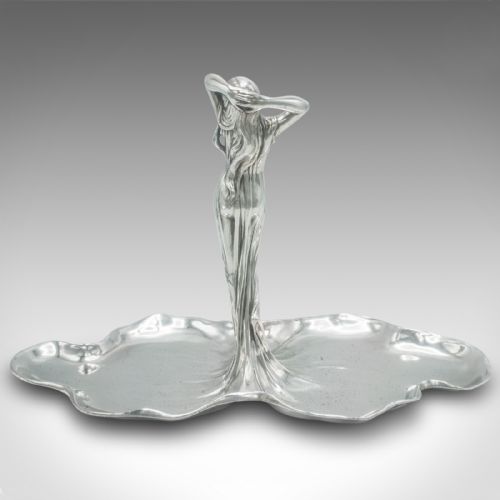 fig 3. A silver-toned Art Nouveau metal card tray featuring a central sculpted maiden figure with flowing hair standing atop a shaped lily pad base.