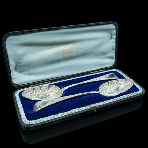 fig 1. A pair of antique Georgian hallmarked sterling silver dessert spoons with ornate repousse foliage decoration in the bowls and stems.