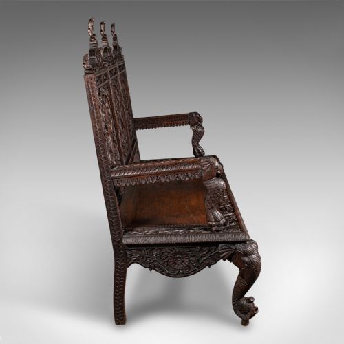 fig 2. A large dark teak three-seat bench featuring arched back panels with relief carvings, beast-form armrests, and carved legs.