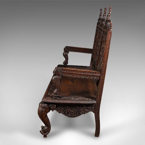 fig 5. A large dark teak three-seat bench featuring arched back panels with relief carvings, beast-form armrests, and carved legs.