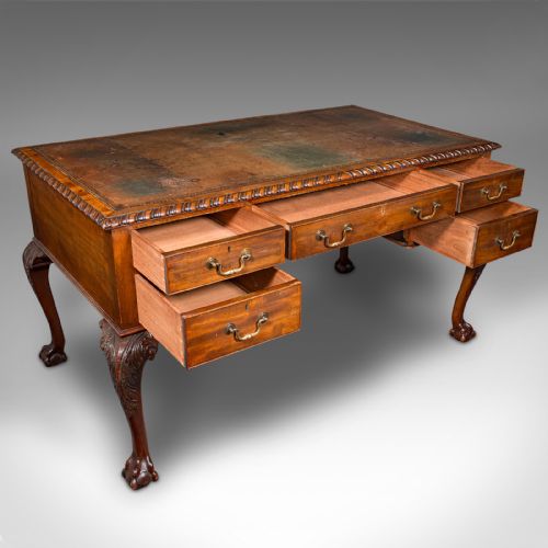fig 1. An antique Edwardian mahogany writing desk featuring an inset leather top, carved gadrooned edge, five drawers with brass handles, and cabriole legs terminating in ball and claw feet.