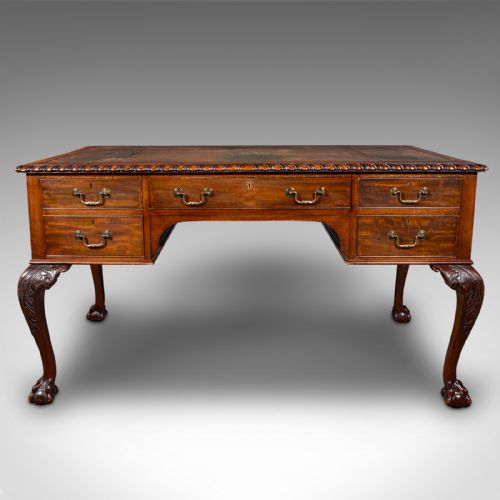 fig 2. An antique Edwardian mahogany writing desk featuring an inset leather top, carved gadrooned edge, five drawers with brass handles, and cabriole legs terminating in ball and claw feet.