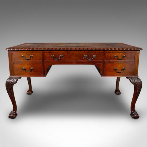 fig 4. An antique Edwardian mahogany writing desk featuring an inset leather top, carved gadrooned edge, five drawers with brass handles, and cabriole legs terminating in ball and claw feet.