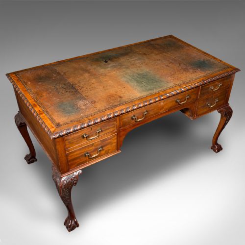 fig 6. An antique Edwardian mahogany writing desk featuring an inset leather top, carved gadrooned edge, five drawers with brass handles, and cabriole legs terminating in ball and claw feet.