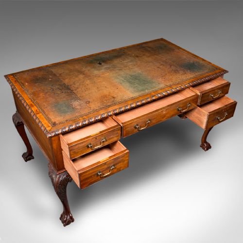 fig 7. An antique Edwardian mahogany writing desk featuring an inset leather top, carved gadrooned edge, five drawers with brass handles, and cabriole legs terminating in ball and claw feet.