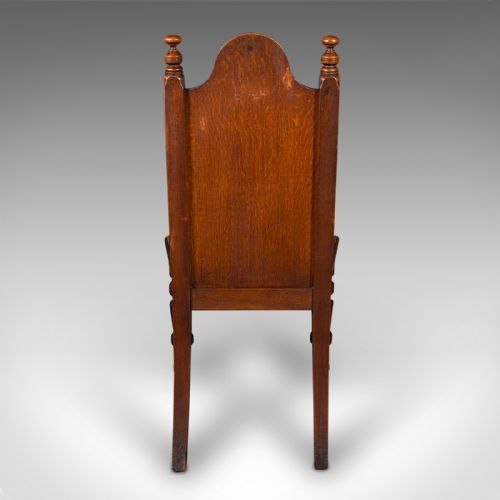 fig 2. A Victorian Scottish oak Gothic Revival hall chair featuring a carved arched back, turned front legs on castors, and cross motifs on the frame.