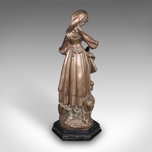 fig 3. An antique bronzed plaster statue depicting a standing woman in rustic attire holding a basket alongside a small dog on a dark octagonal plinth.