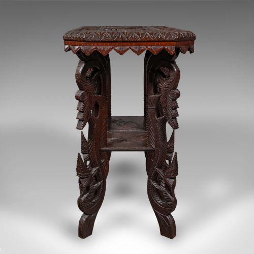 fig 2. A dark brown hand-carved teak occasional table featuring animal relief carving on top, pierced foliage legs, and a lower shelf tier.