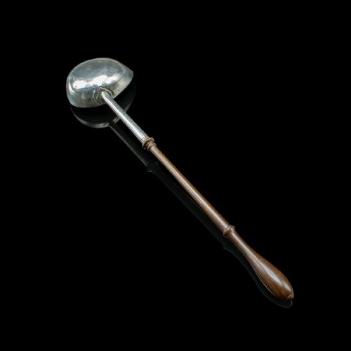 fig 1. An antique Georgian silver toddy ladle featuring a round bowl with an internal partition and a long turned wooden handle.