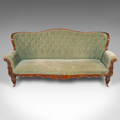 fig 1. An antique seven-foot wide English settee featuring sage green velvet button-back upholstery, a carved walnut frame, and scrolled legs on brass castors.
