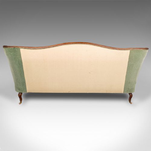fig 2. An antique seven-foot wide English settee featuring sage green velvet button-back upholstery, a carved walnut frame, and scrolled legs on brass castors.