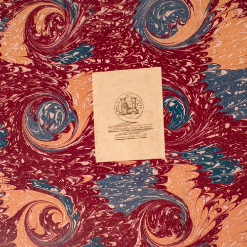 fig 1. A large antique book bound in red leather and marbled brown paper with gold gilt detailing along the spine.