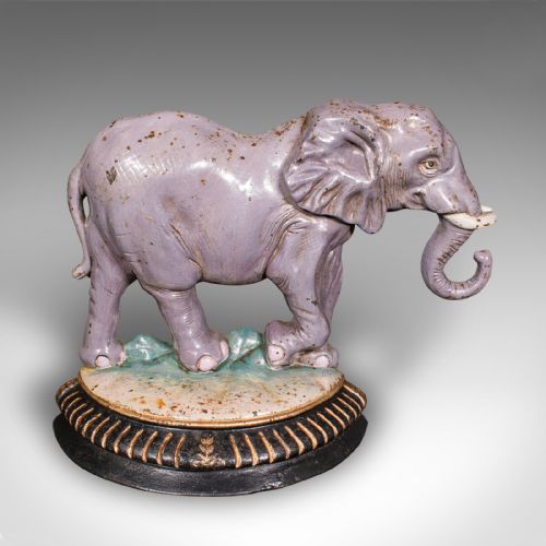 fig 1. A Victorian cast iron doorstop depicting an elephant with its trunk raised standing on a painted oval base.